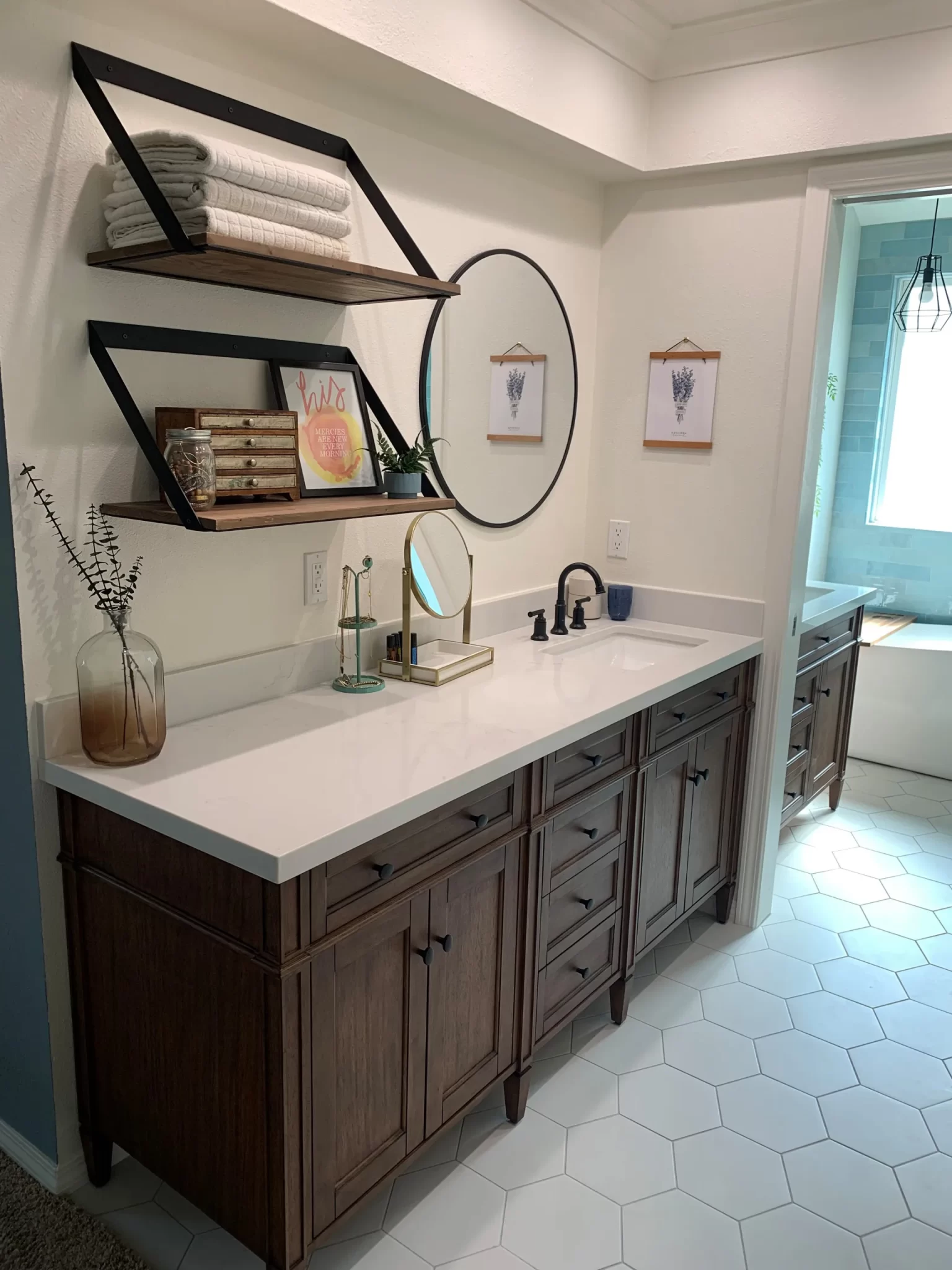 bathroom-remodels-11 Modern bathroom with wooden cabinets, round mirror, shelves with towels, and hexagon tile floor.