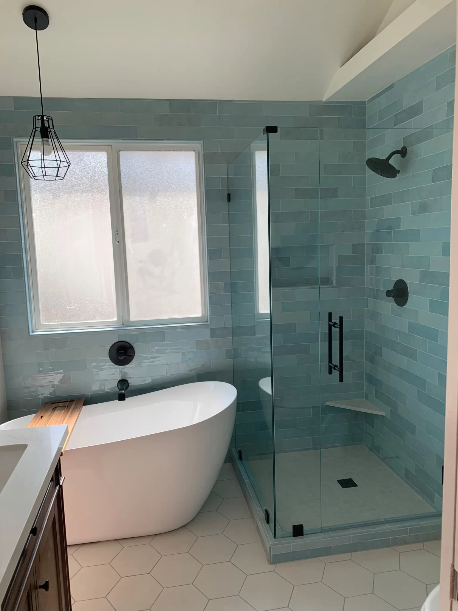 bathroom-remodels-13 Modern bathroom with a freestanding tub, glass shower, blue tile walls, and hexagon floor tiles.