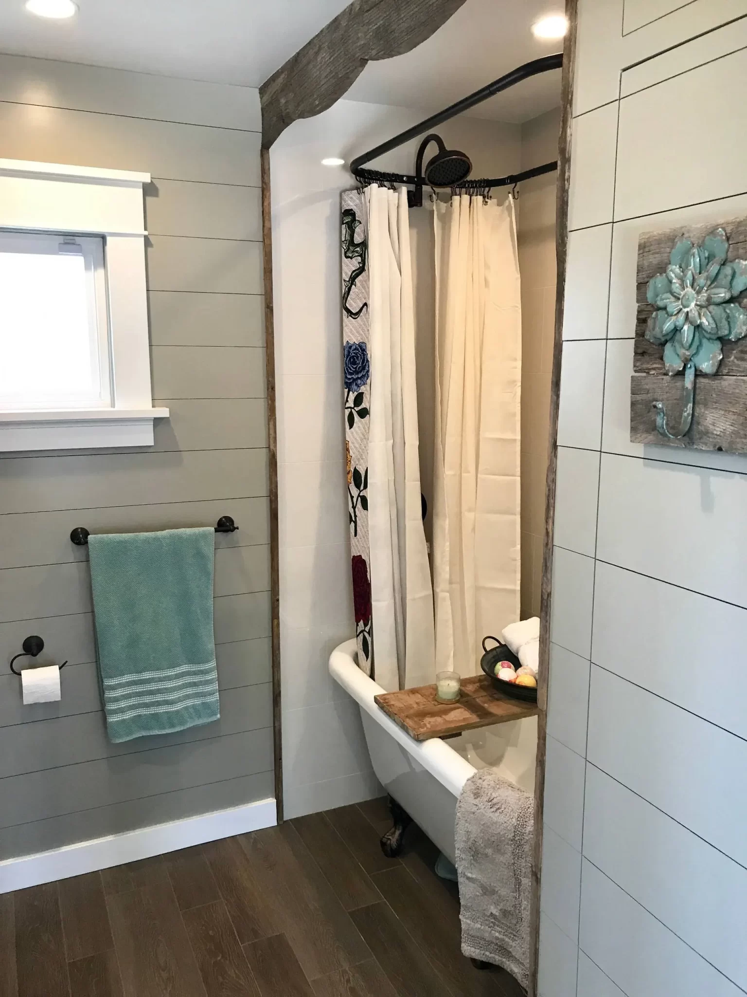 bathroom-remodels-2 Farmhouse bathroom with clawfoot tub, floral shower curtain, towel rack, and flower wall art.