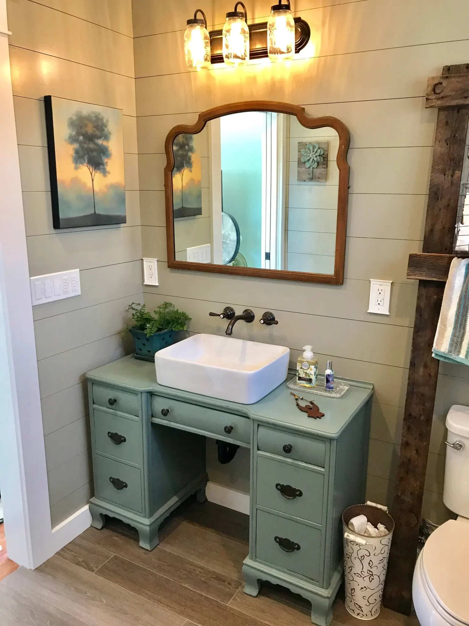 bathroom-remodels-3 Vintage-style bathroom vanity with a vessel sink, wood-framed mirror, and rustic decor accents.
