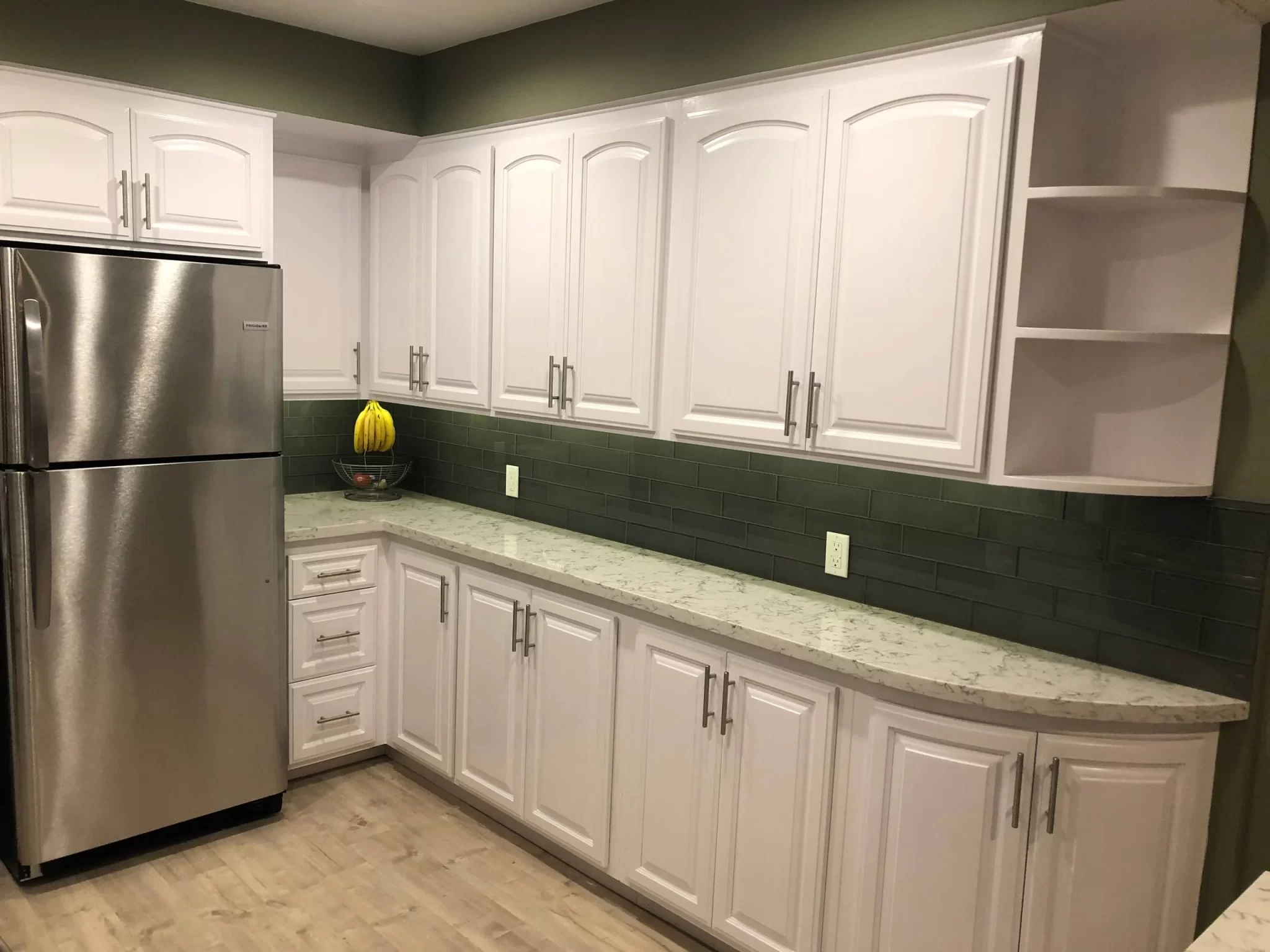 custom-cabinetry-carpentry-11 Modern kitchen with white cabinets, green tile backsplash, and stainless steel refrigerator.