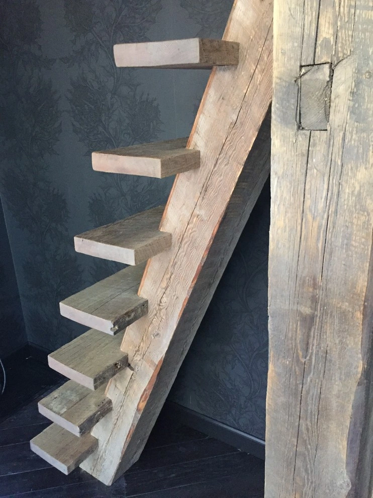custom-cabinetry-carpentry-4 Floating wooden staircase with thick, rustic steps against a dark-patterned wall.