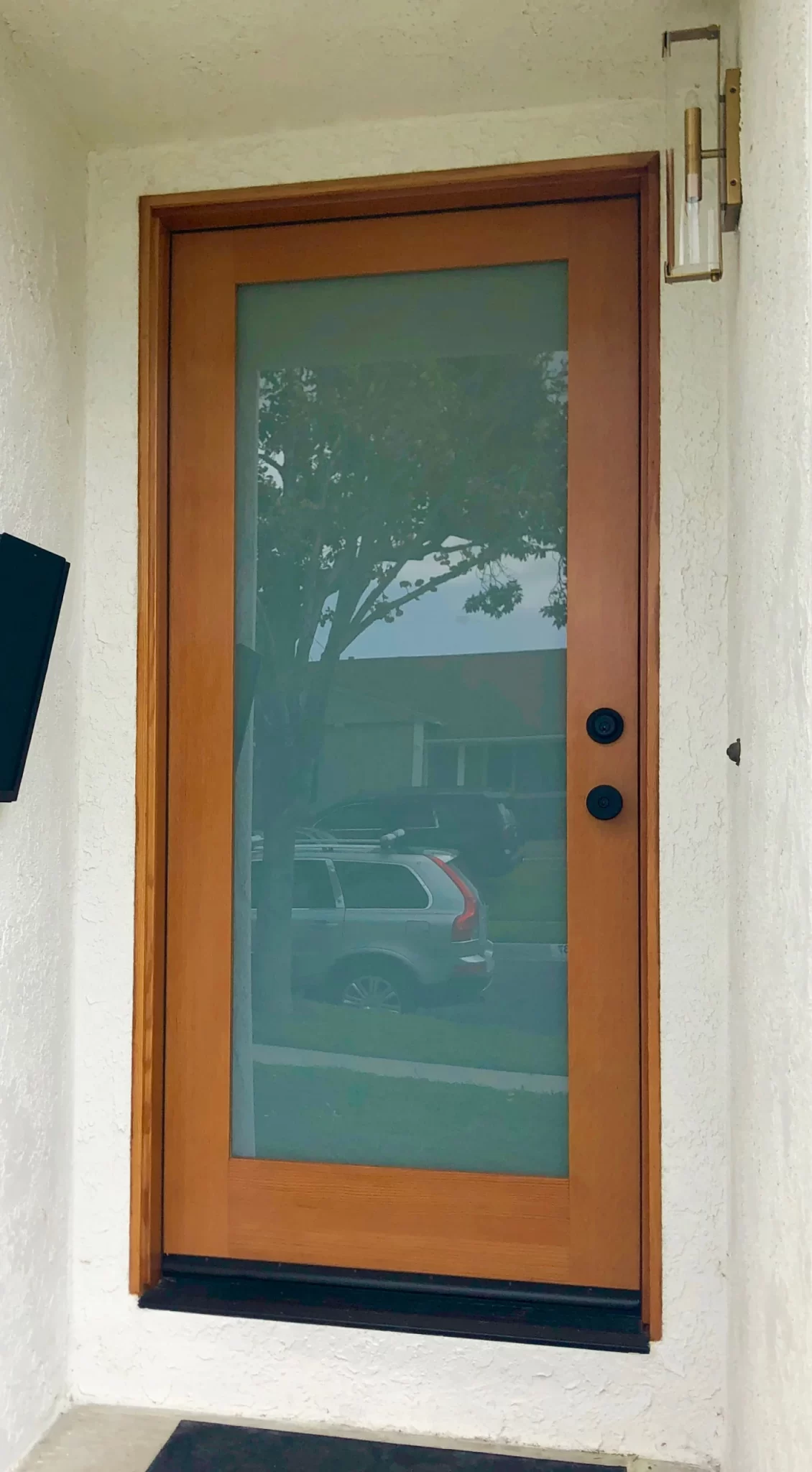 doors-and-windows-3 Wood-framed glass front door with two black doorknobs, reflecting a car and tree outside.