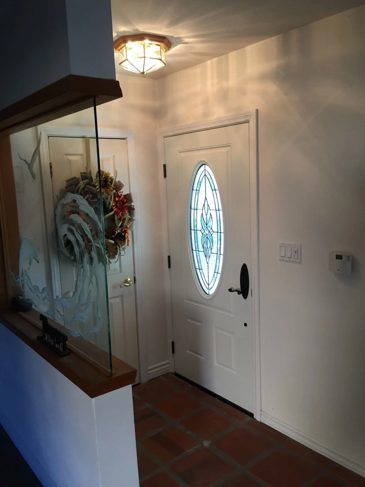 doors-and-windows-9 Entryway with a white door with an oval glass panel, tile floor, and a glass panel with wave art on the left.