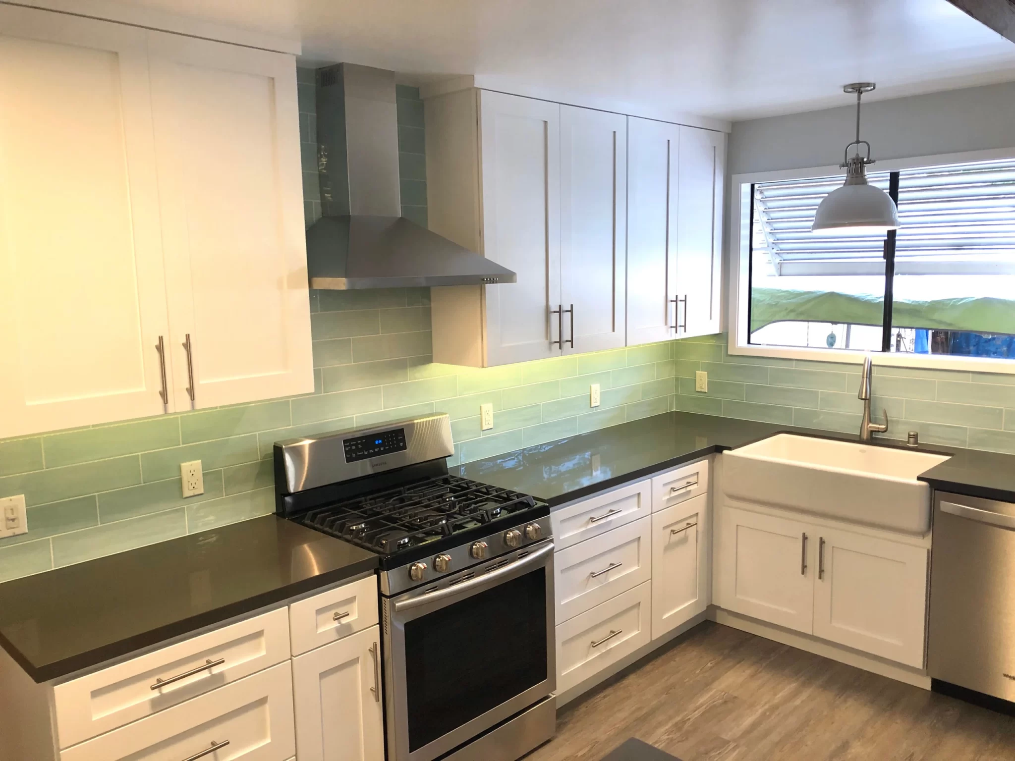 kitchen-remodels-13 Modern kitchen with white cabinets, stainless steel appliances, and light green tile backsplash.