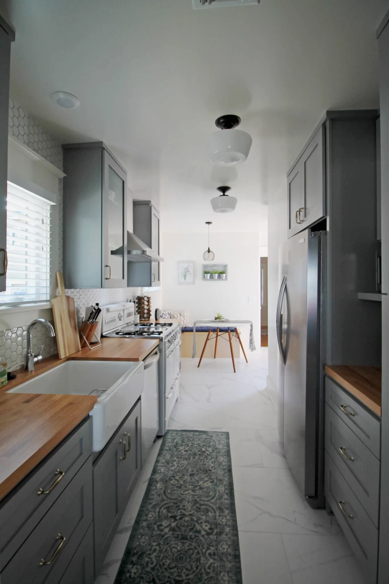 kitchen-remodels-2 Narrow kitchen with gray cabinets, wood countertops, farmhouse sink, and stainless steel appliances.