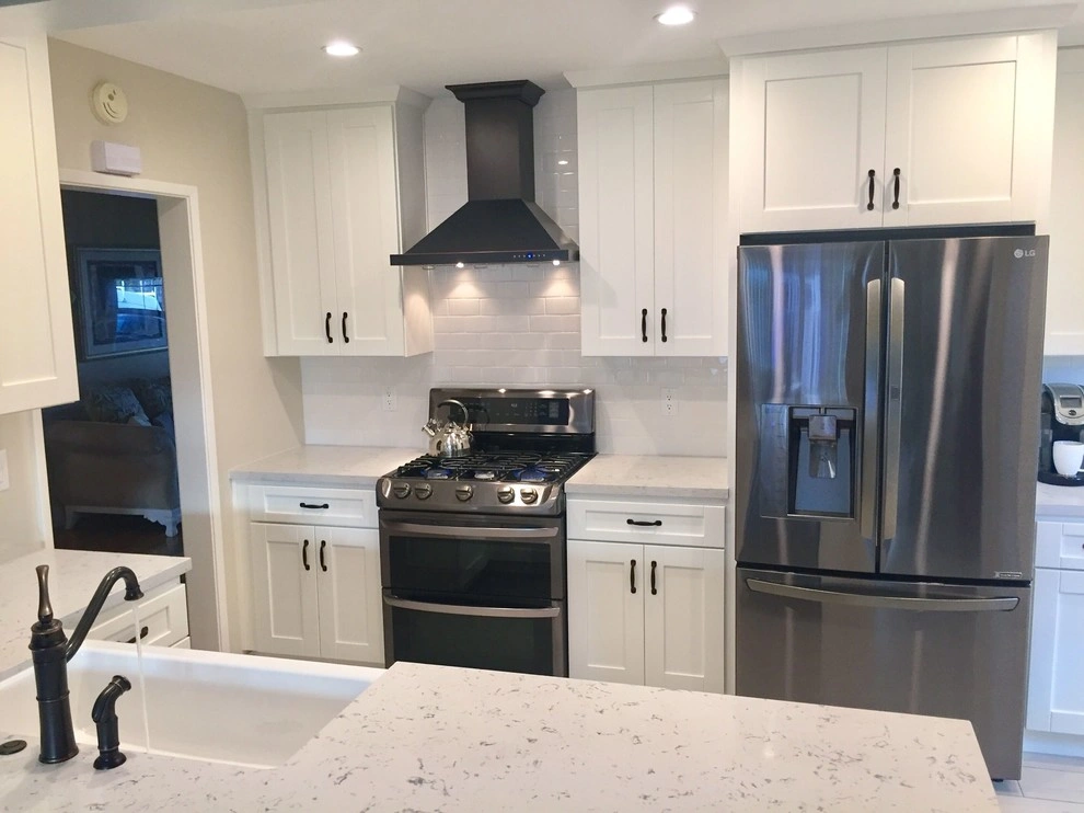 kitchen-remodels-5 Modern kitchen with white cabinets, stainless steel appliances, and a center island with a sink.