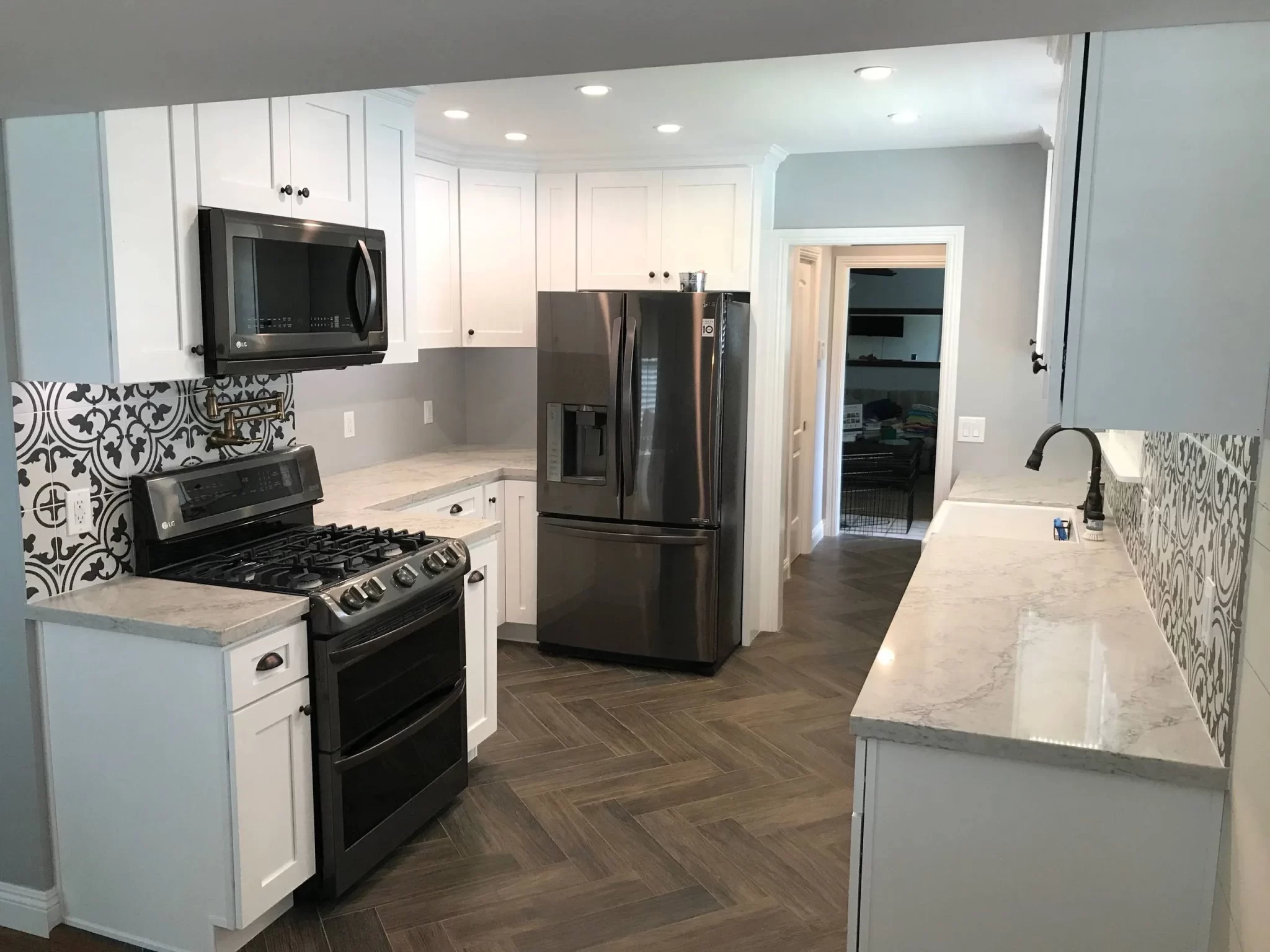 kitchen-remodels-6 Modern kitchen with white cabinets, stainless steel appliances, and patterned backsplash tiles.