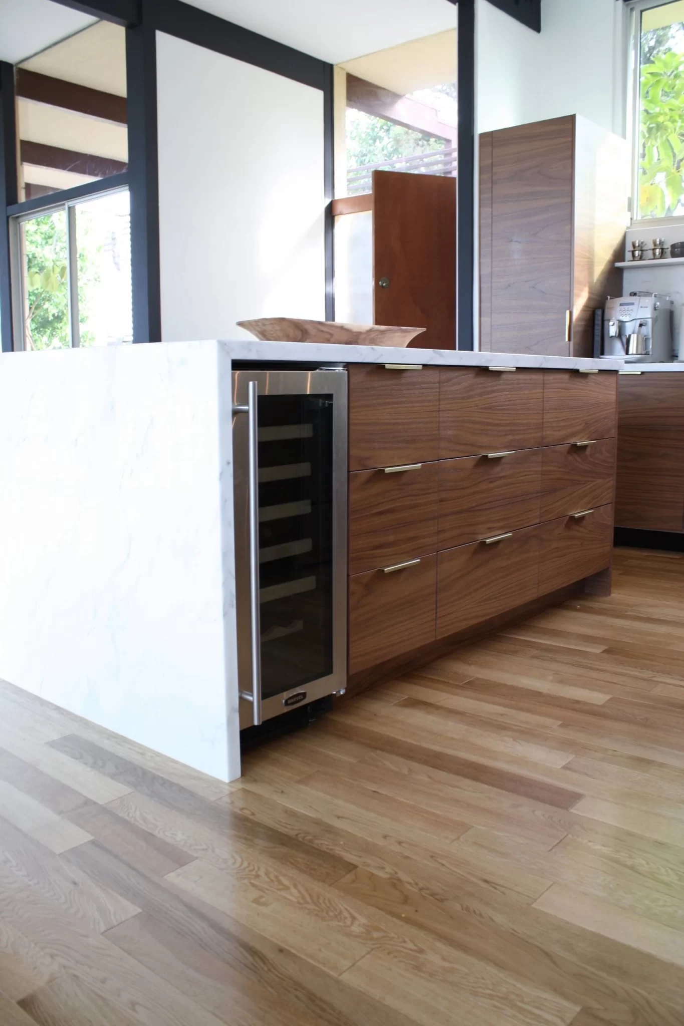 kitchen-remodels-8 Modern kitchen island with wood cabinets, a built-in wine fridge, and light wood flooring.