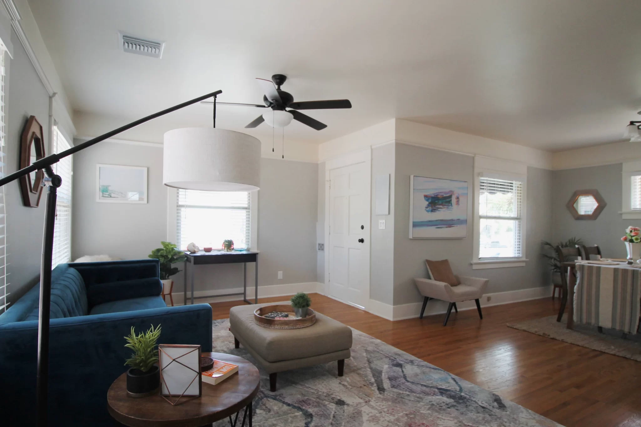 living-spaces-5 Bright living room with a blue sofa, round ottoman, modern decor, and hardwood floors.
